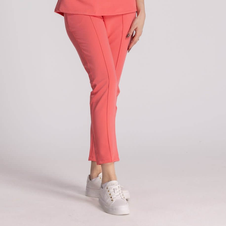 Pantaloni Elastici Elise în nuanță corai, confortabili, asortați cu adidași albi, ideal pentru un look profesional.