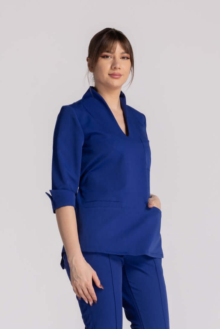 Bluza Elastica Elise - bluză medicală albastră cu guler shal și buzunare pentru instrumente.